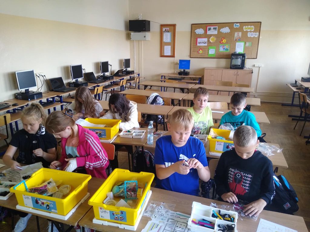 Uczniowie w sali lekcyjnej budują modele z klocków Lego