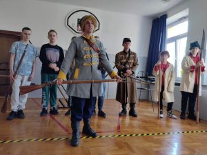 Pokaz historyczny - uczniowie na sali gimnaztycznej przebrani w stroje.