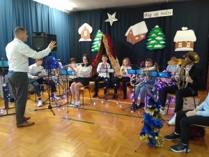 Uczniowie graja na instrumentach w tle dekoracja świąteczna