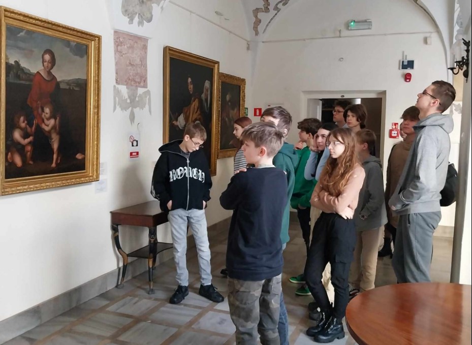 Uczniowie w galerii oglądają wiszące na ścianach obrazy.