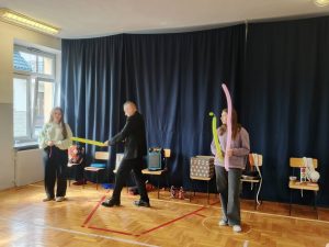 Iluzjonista wykonuje sztuczki z balonami asystują mu dwie uczennice.