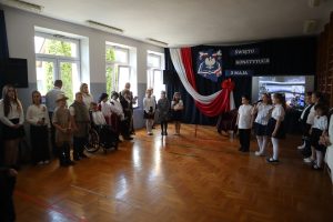 Uczniowie podczas akademii w tle napis święto konstytucji 3 maja