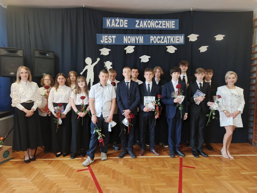 Absolwenci szkoły z wychowawcą i dyrektorem szkoły w tle napis " każde zakończenie jest nowym początkiem.